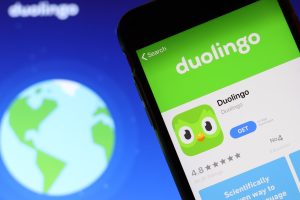 Mobile phone with Duolingo icon on screen close up with website on laptop. Blurred background with Duolingo logo. Los Angeles, California, USA - 9 November 2019, Illustrative Editorial